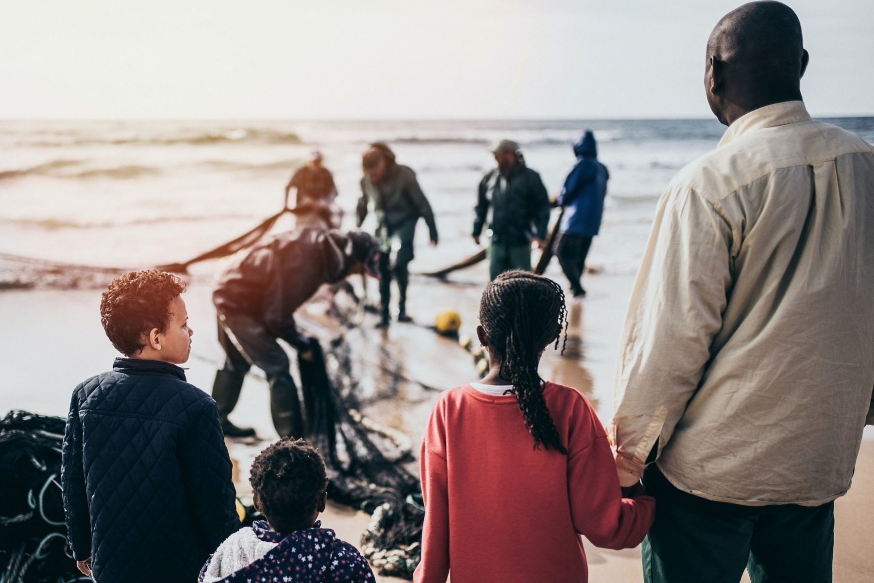 Refugees on a shoreline. One man and three children